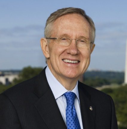 Harry Reid wearing a blue suit and tie and smiling. 